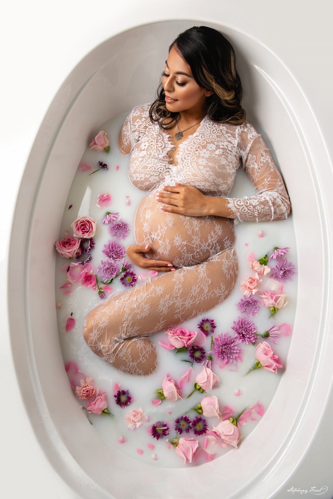 Retrato artístico de embarazo en una tina con agua lechosa y pétalos