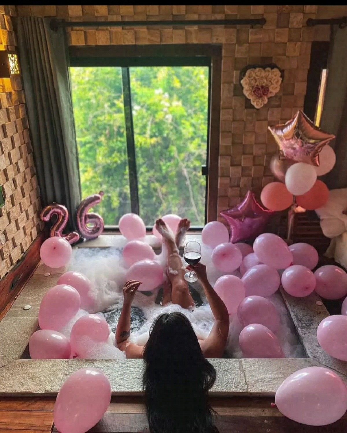 Cumpleaños celebrado en una suite con bañera de espuma y globos rosados