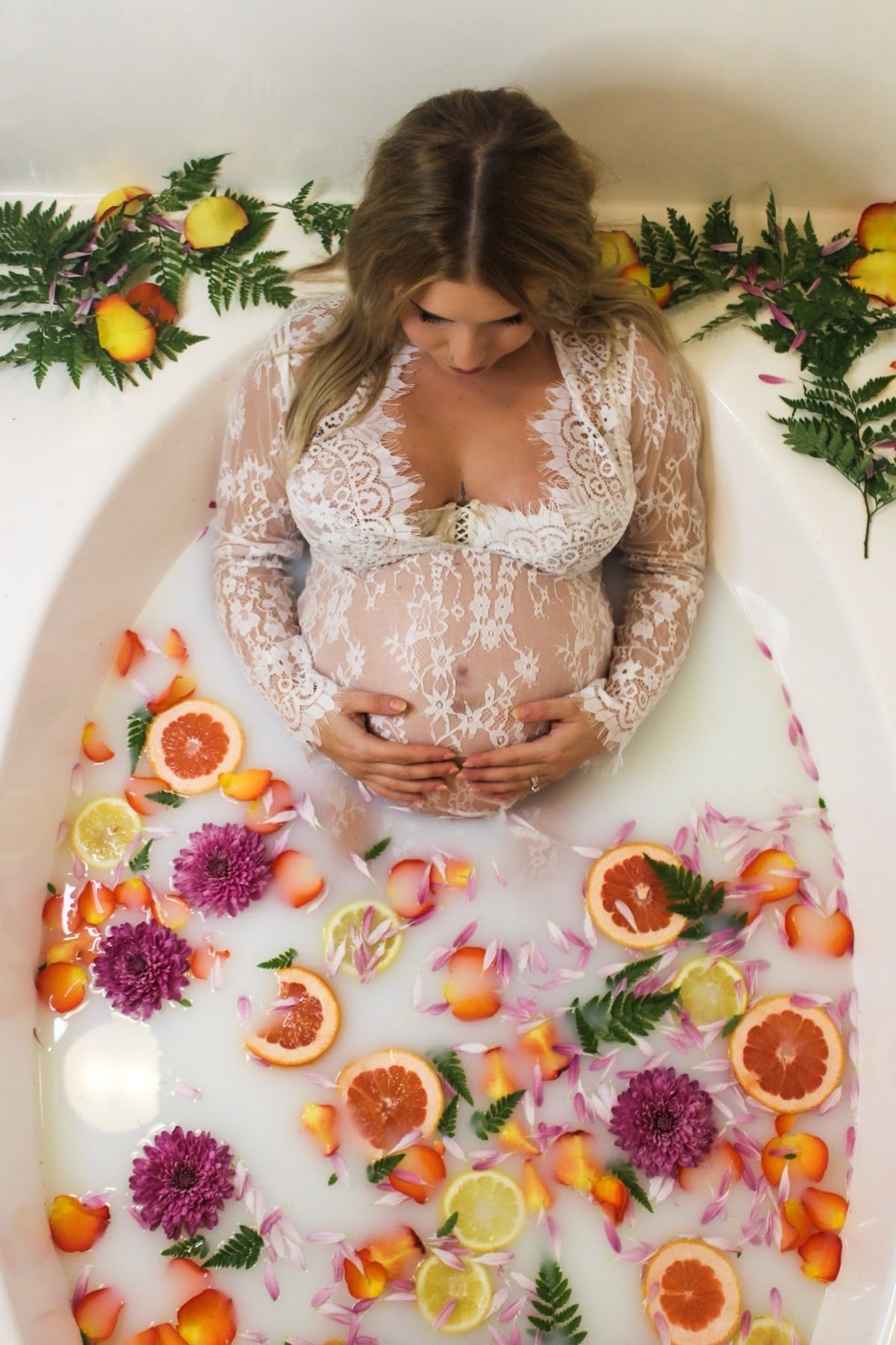 Sesión fotográfica de embarazo con flores y cítricos flotando en el agua